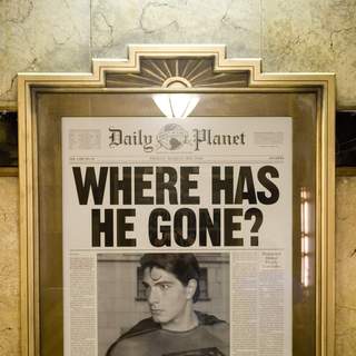 In the lobby of the Daily Planet building, a framed copy of a front page asks the question, 